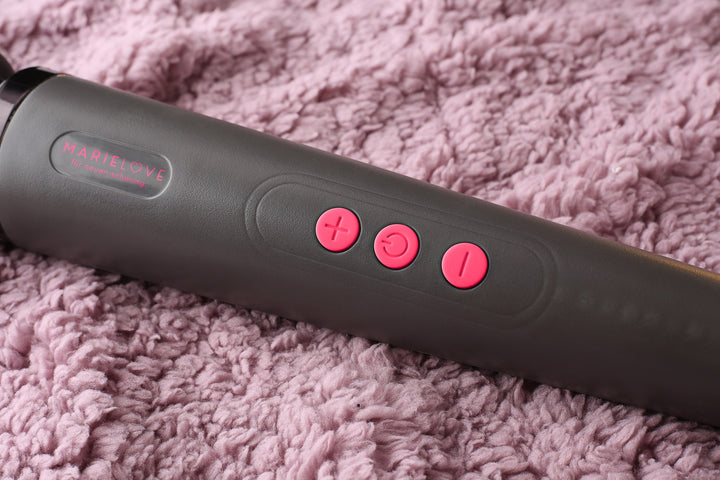 Schwarzer Vibrator auf rosa Decke