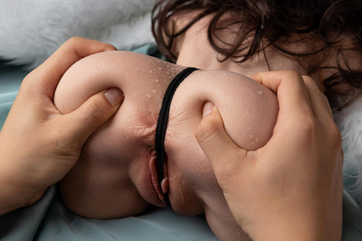 Hände drücken Sexpuppen-Gesäß zusammen