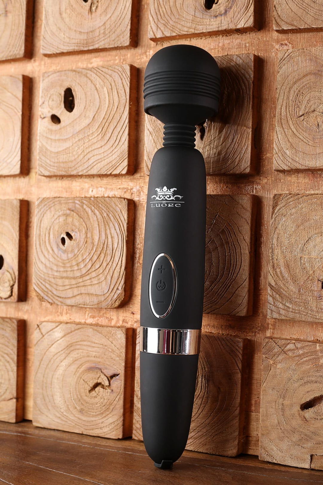 Schwarzer Vibrator vor Holzwand